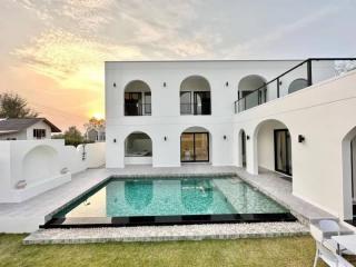 Exterior view of a modern two-story house with private pool at sunset