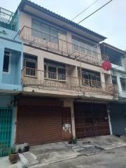 Three-story residential building with balconies and shuttered shops on the ground floor