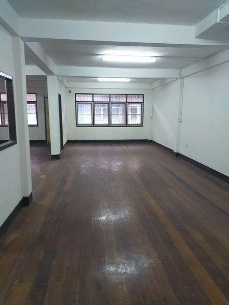 Spacious empty interior of a building with wooden flooring and multiple windows