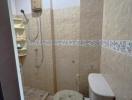 Small bathroom with shower, toilet, and beige tiling