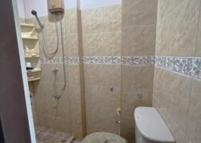 Small bathroom with shower, toilet, and beige tiling