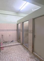 Empty bathroom with tiled floor and walls, fluorescent lighting, and partitioned area