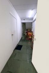 Narrow hallway with green flooring and stored items at the end