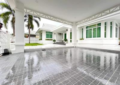 Spacious front porch of a suburban house with tiled flooring and white columns
