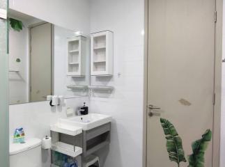 Modern clean bathroom with white tiles, sink, mirror, and storage space