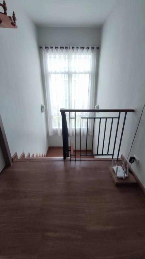 Spacious and well-lit staircase area leading to the lower floor with wooden flooring