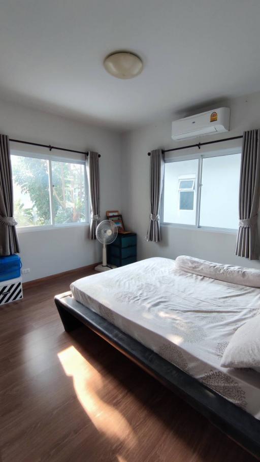 Spacious and well-lit bedroom with large windows and a comfortable bed