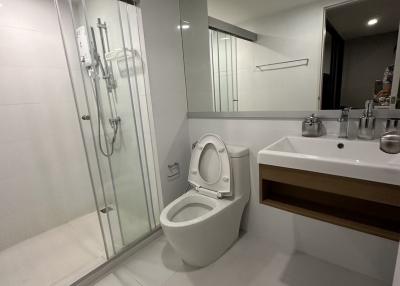 Modern bathroom with glass shower enclosure, toilet, and sink