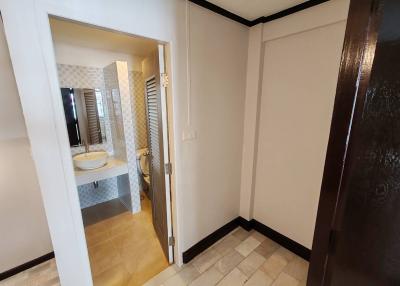Entrance hallway leading to a modern bathroom with a visible sink and mirror