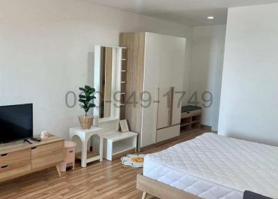Spacious and modern bedroom with ample natural light featuring a large bed, wardrobe, TV, and wooden flooring