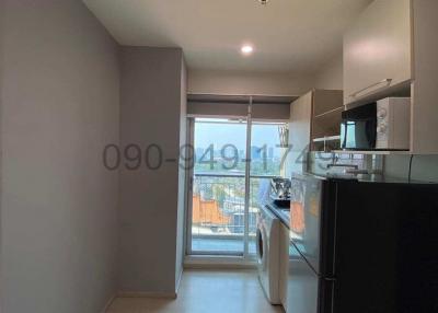 Compact kitchen leading to a balcony with natural light