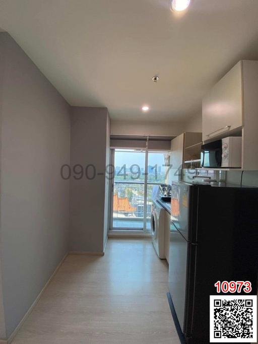 Compact kitchen leading to a balcony with natural light