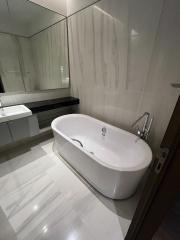 Modern bathroom interior with freestanding bathtub and reflective tiles