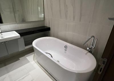 Modern bathroom with spacious bathtub, large mirror, and elegant tiling