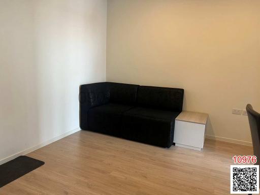 Minimalist living room with a black sofa and wooden flooring