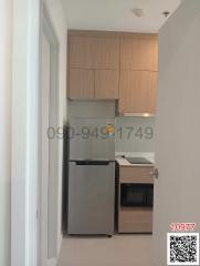 Compact modern kitchen with wood cabinets and stainless steel refrigerator