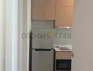 Compact modern kitchen with wood cabinets and stainless steel refrigerator