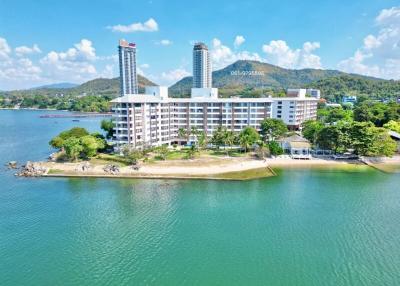 Aerial view of a waterfront residential building with surrounding natural landscape