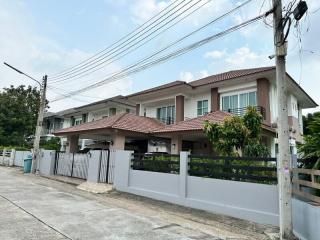 Tan two-story residential home with tile roof and gray perimeter wall