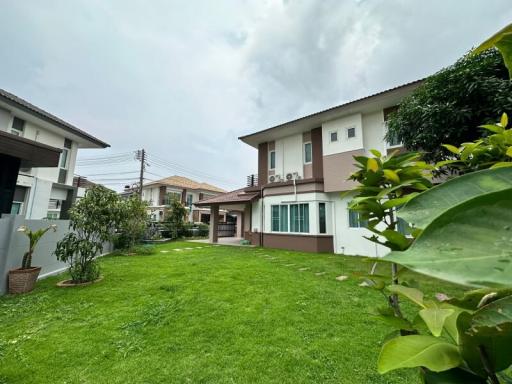 Lush green lawn in front of residential houses under cloudy sky