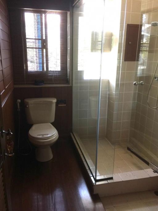 Compact bathroom with shower, toilet, and wooden flooring