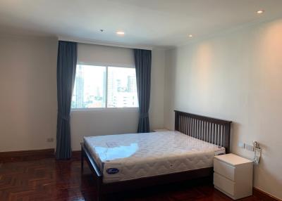Spacious bedroom with hardwood floors and city view
