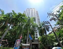 High-rise apartment building facade with surrounding greenery under a clear blue sky