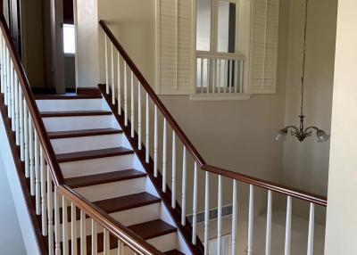Elegant wooden staircase with white balustrade and chandelier in a residential home