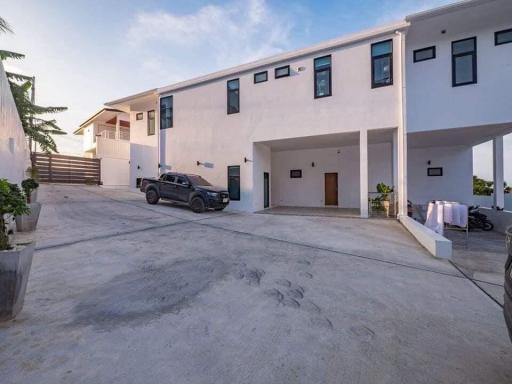 Modern two-storey residential building with spacious driveway and vehicles