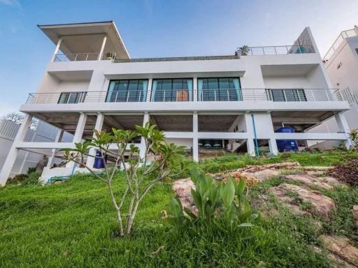 Exterior view of a modern multi-level house with balconies and a landscaped garden