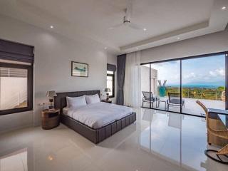 Spacious bedroom with large bed, glossy floor tiles, and a scenic view