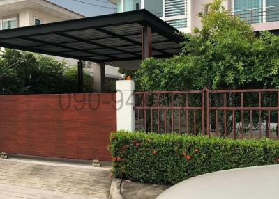 Exterior view of a residential house with a carport and greenery