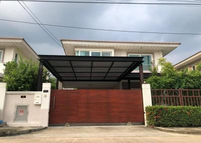 Modern two-story house with a large wooden gate and carport