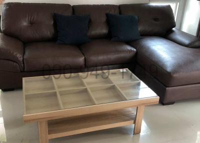 Brown leather sectional sofa with blue cushions and a wooden coffee table in a modern living room