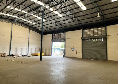 Spacious commercial warehouse interior with high ceiling and large shutter door
