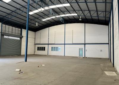 Spacious industrial warehouse interior with high ceiling and large shutter door