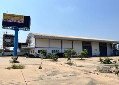 Exterior view of a commercial warehouse with a large parking area under a clear blue sky