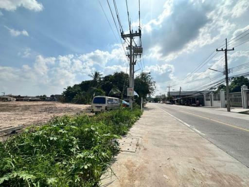 Empty lot next to a paved road under a blue sky with clouds