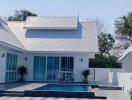 White single-story house with swimming pool and patterned tile patio