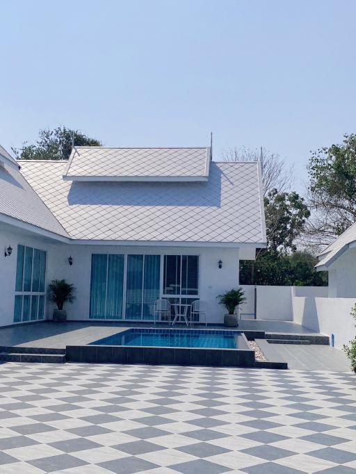 White single-story house with swimming pool and patterned tile patio
