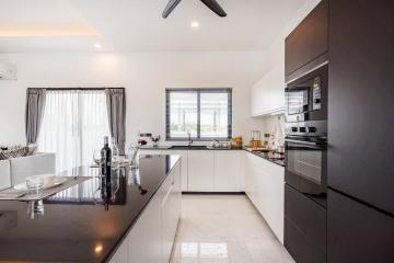 Modern kitchen with white countertops, dark cabinets, and stainless steel appliances