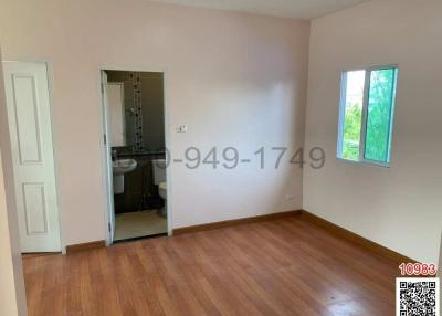 Spacious bedroom with hardwood floors, a large window, and an en suite bathroom