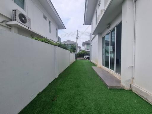 Artificial grass backyard of a modern white residential building with clear sky