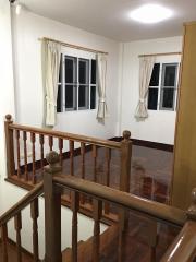 Bright staircase landing with wooden banister and polished floor