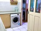 Compact kitchen space with white goods and tiled flooring