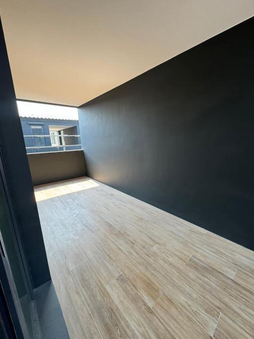 Modern balcony with wooden flooring and dark wall paint