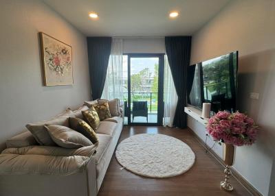 Cozy living room with sofa, modern TV, and balcony access