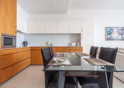 Modern kitchen with attached dining area featuring wooden cabinets and a glass dining table