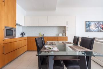 Modern kitchen with attached dining area featuring wooden cabinets and a glass dining table