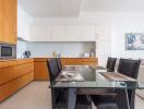 Modern kitchen with attached dining area featuring wooden cabinets and a glass dining table